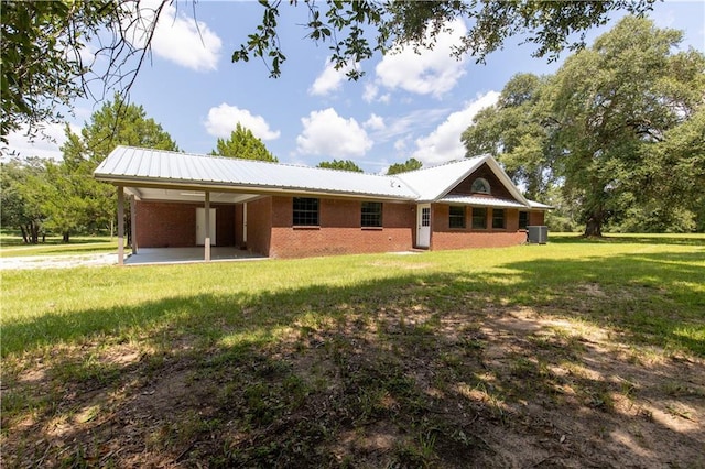 rear view of house featuring brick siding, metal roof, a carport, and a yard