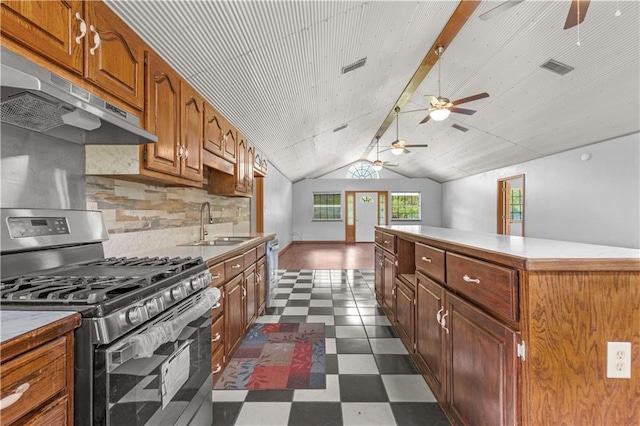 kitchen with ceiling fan, stainless steel gas range oven, tasteful backsplash, sink, and lofted ceiling with beams