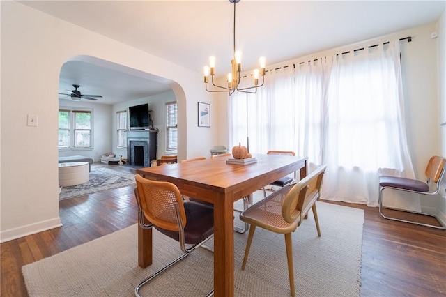 dining area with ceiling fan with notable chandelier and dark hardwood / wood-style floors