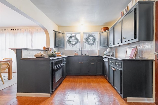 kitchen with kitchen peninsula, decorative backsplash, sink, light hardwood / wood-style floors, and oven