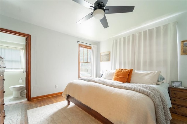 bedroom with ceiling fan, light wood-type flooring, and ensuite bath