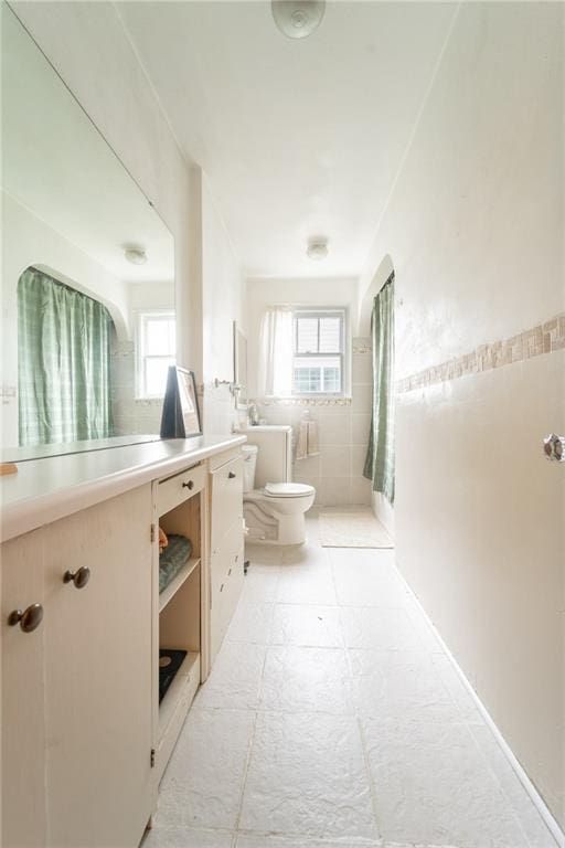 bathroom featuring a wealth of natural light, vanity, tile walls, and toilet