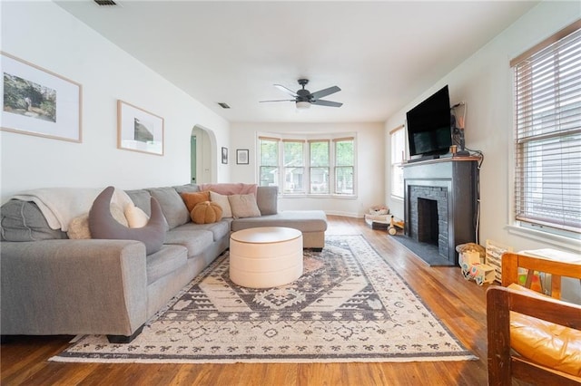 living room with hardwood / wood-style flooring, a brick fireplace, and ceiling fan