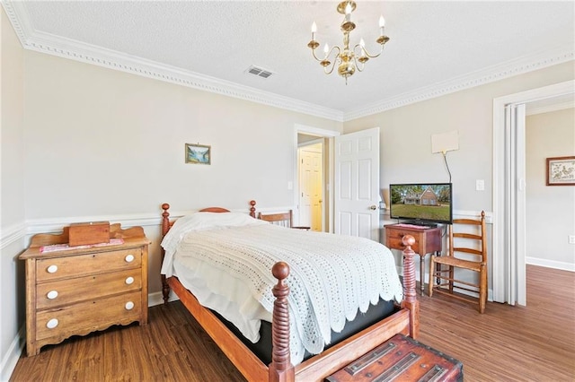 bedroom featuring a textured ceiling, ornamental molding, dark wood-type flooring, and a chandelier