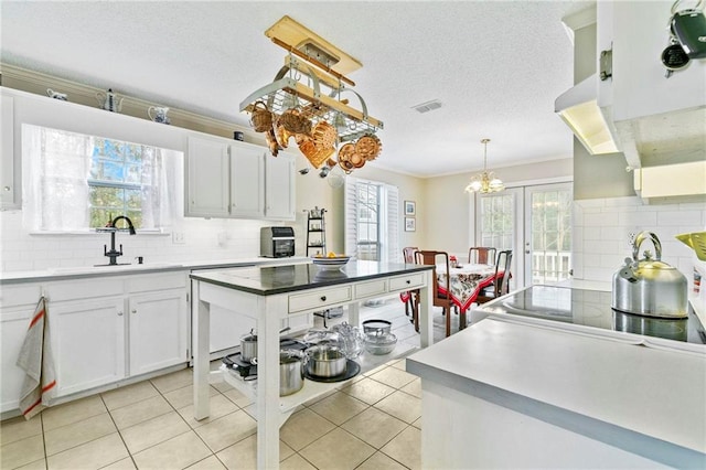 kitchen featuring pendant lighting, decorative backsplash, white cabinetry, and crown molding