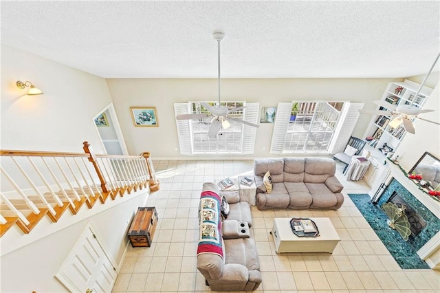 tiled living room featuring a high end fireplace, a textured ceiling, and ceiling fan