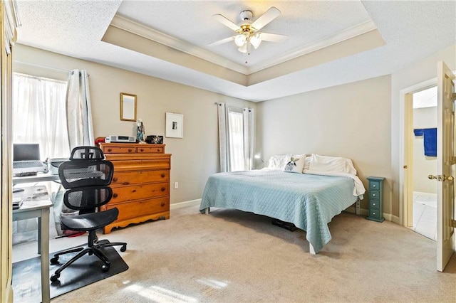 carpeted bedroom with a tray ceiling, ceiling fan, and crown molding