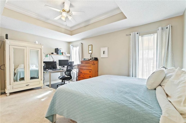 carpeted bedroom featuring a tray ceiling, ceiling fan, crown molding, and a textured ceiling