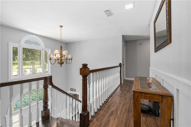 corridor with a notable chandelier, dark wood-type flooring, and plenty of natural light