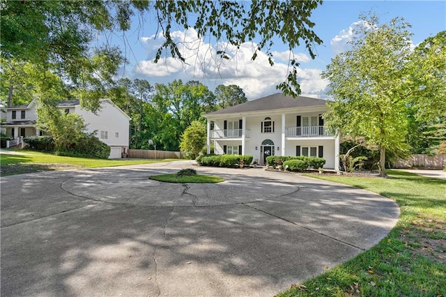 view of front of property with a balcony and a front lawn