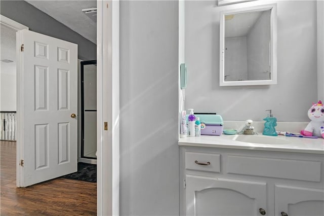 bathroom with wood-type flooring, a shower with door, and large vanity