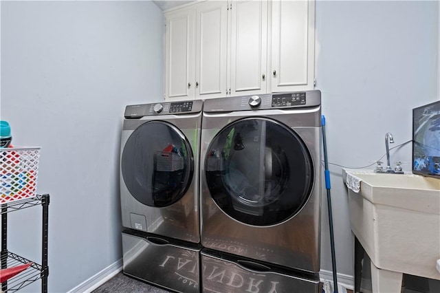 clothes washing area featuring cabinets, sink, and washer and clothes dryer