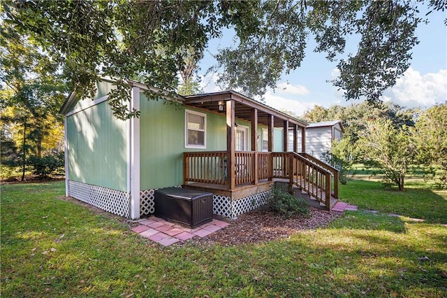 rear view of house with covered porch and a yard