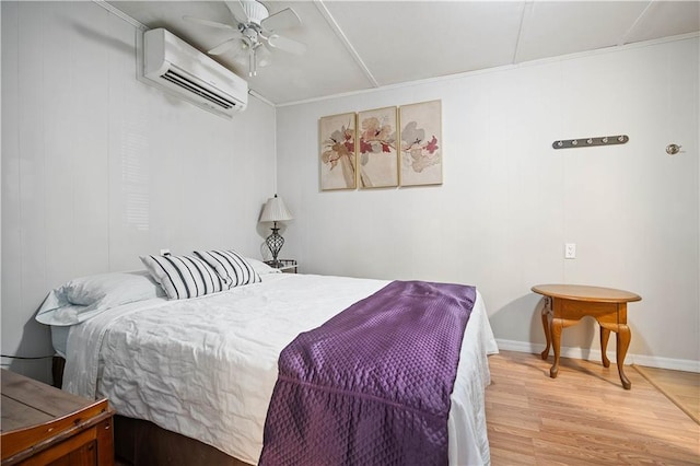 bedroom featuring a wall mounted air conditioner, wood-type flooring, and ceiling fan