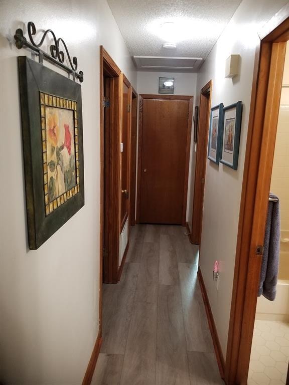 hall with hardwood / wood-style floors and a textured ceiling