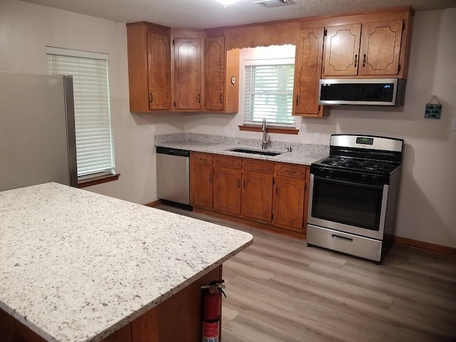 kitchen with sink, light hardwood / wood-style floors, a textured ceiling, and appliances with stainless steel finishes