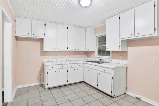 kitchen with white cabinetry, tile counters, and sink