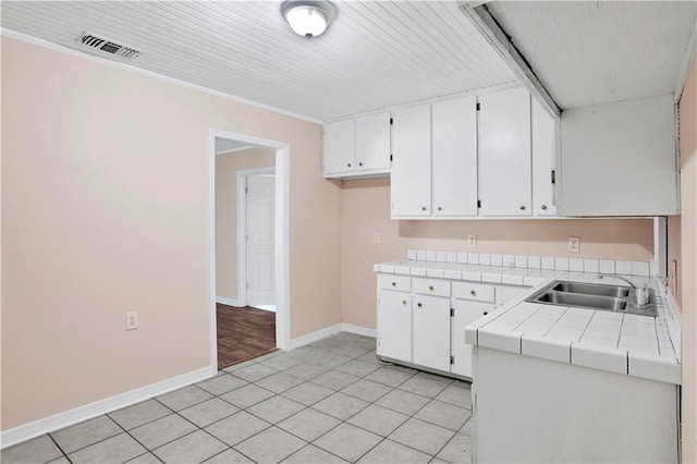 kitchen with white cabinetry, tile counters, light tile patterned flooring, and sink