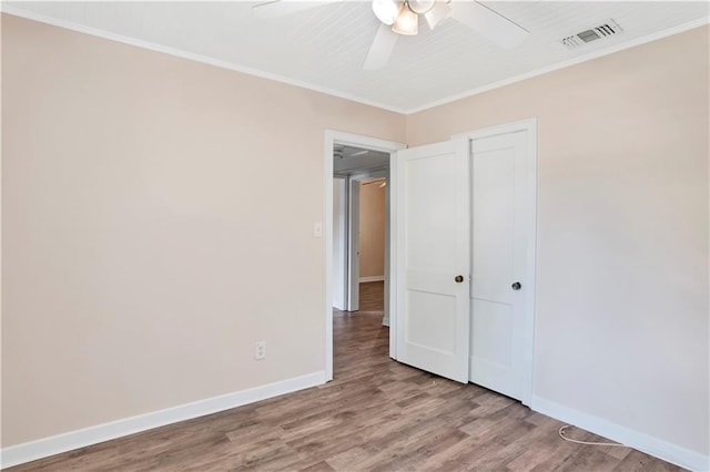 unfurnished bedroom featuring crown molding, ceiling fan, a closet, and hardwood / wood-style floors