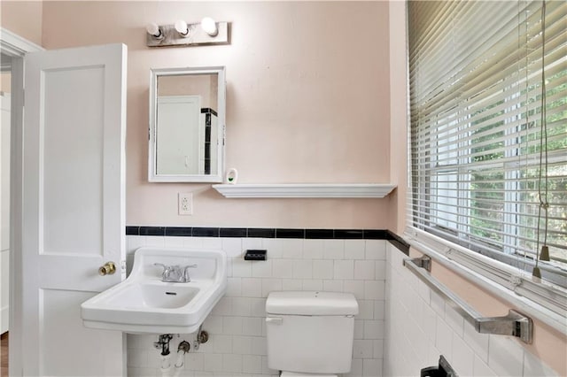 bathroom featuring toilet, tile walls, and sink