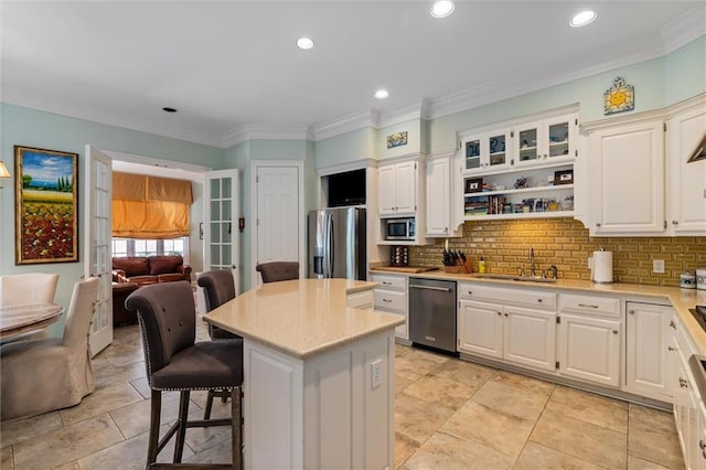 kitchen featuring a breakfast bar, stainless steel appliances, sink, white cabinetry, and a kitchen island