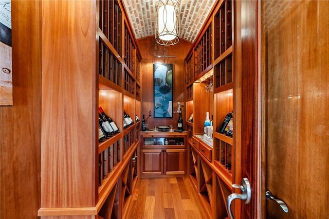 wine cellar with light hardwood / wood-style flooring, brick ceiling, and vaulted ceiling