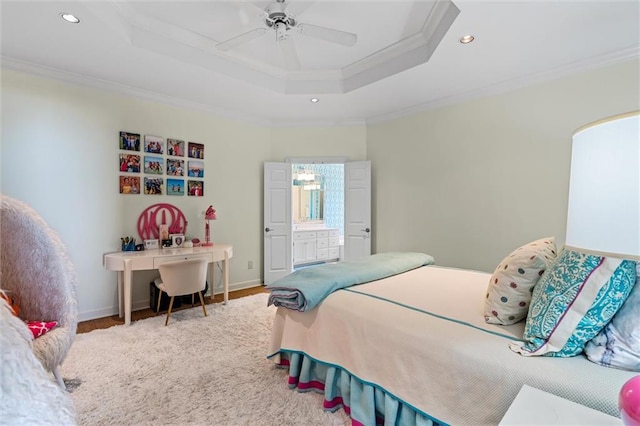 bedroom with a raised ceiling, ceiling fan, crown molding, hardwood / wood-style flooring, and connected bathroom