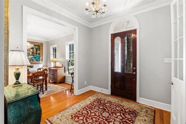 entryway with crown molding, wood-type flooring, and an inviting chandelier