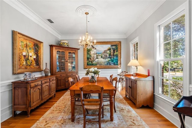 dining space featuring a chandelier, crown molding, and light hardwood / wood-style flooring