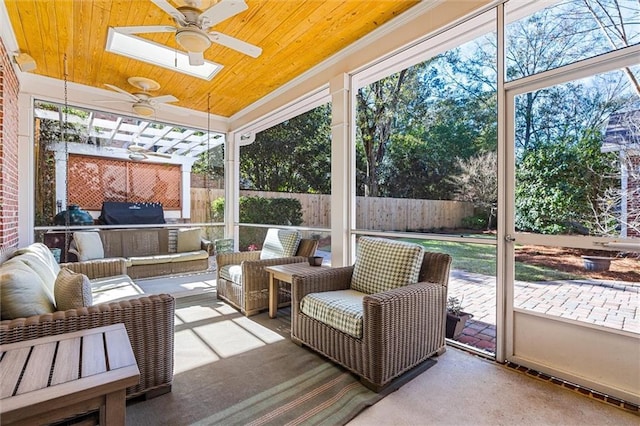 sunroom with ceiling fan, wood ceiling, and a skylight