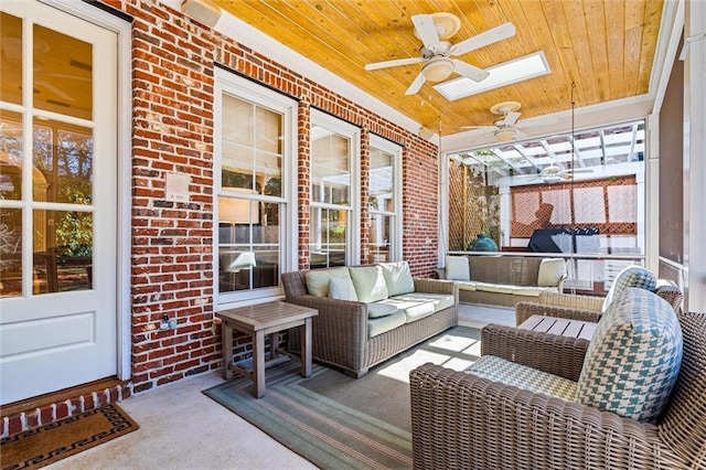 sunroom featuring a skylight, ceiling fan, and wood ceiling