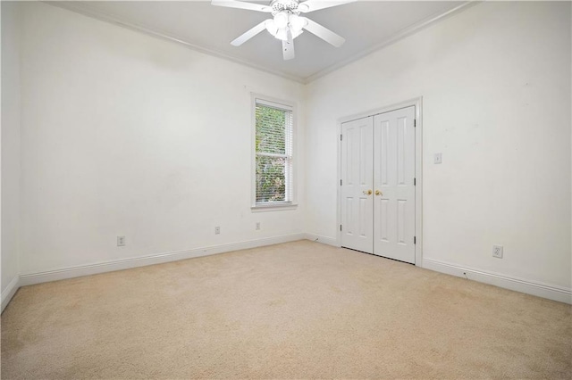 spare room with light carpet, ceiling fan, and ornamental molding