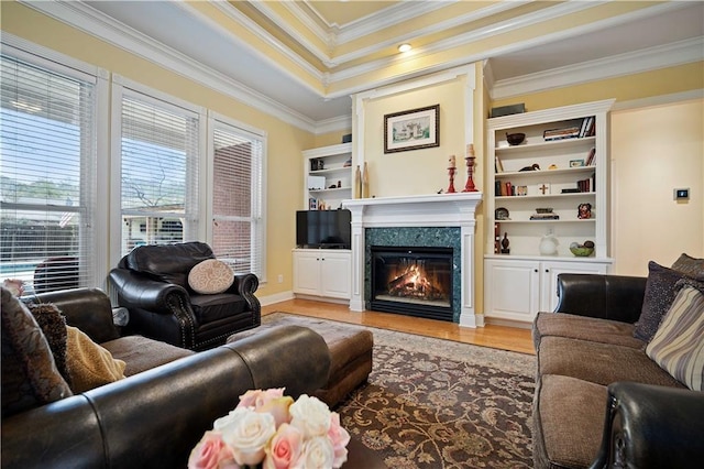 living room with a raised ceiling, a premium fireplace, light hardwood / wood-style flooring, and ornamental molding