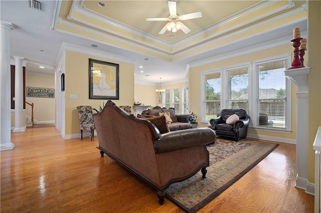 living room with ceiling fan with notable chandelier, ornamental molding, and a tray ceiling