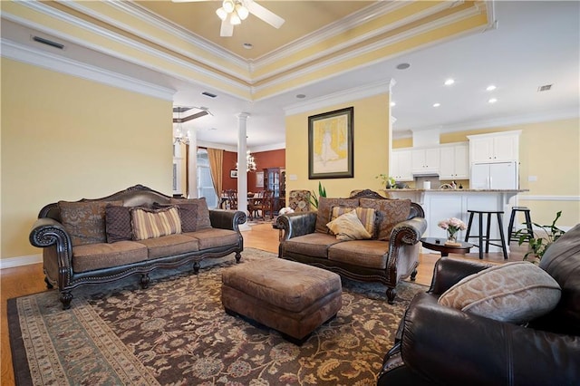 living room with hardwood / wood-style floors, ceiling fan, ornamental molding, and a tray ceiling