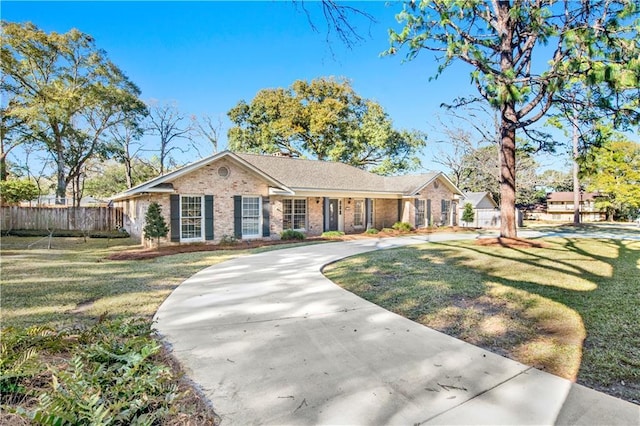 ranch-style home with driveway, brick siding, fence, and a front yard