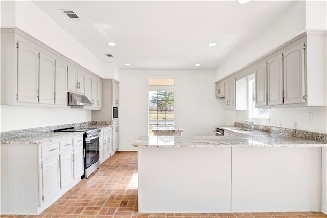 kitchen with kitchen peninsula, light stone countertops, stainless steel electric range, and sink