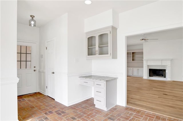 interior space featuring light stone counters, white cabinets, a premium fireplace, and ceiling fan