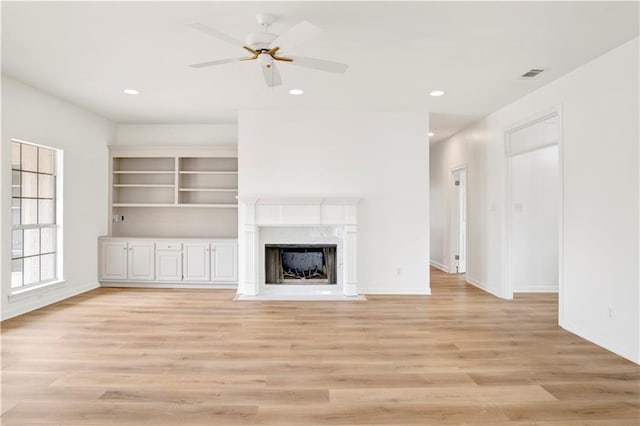 unfurnished living room featuring ceiling fan, light wood-type flooring, and a high end fireplace