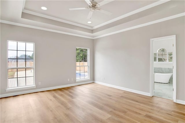 unfurnished room featuring ceiling fan, a wealth of natural light, and a tray ceiling