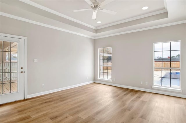 unfurnished room with a healthy amount of sunlight, light hardwood / wood-style flooring, ornamental molding, and a raised ceiling