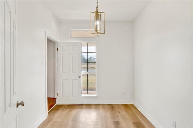 unfurnished dining area featuring a chandelier, light wood-type flooring, and plenty of natural light