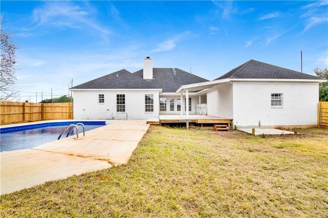 rear view of property with a lawn and a swimming pool side deck