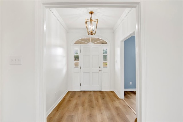 entryway with an inviting chandelier, light wood-type flooring, and ornamental molding