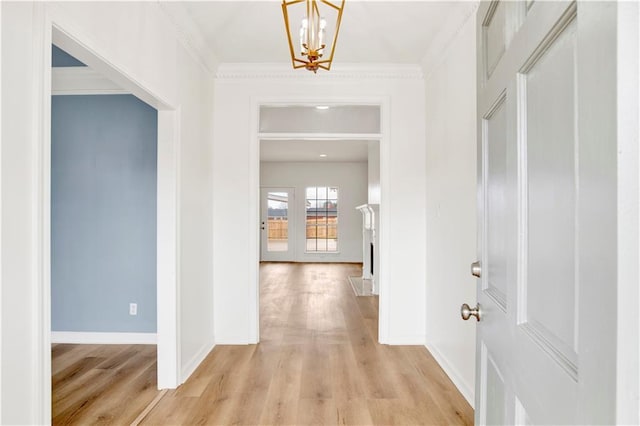 hallway with ornamental molding, a notable chandelier, and light hardwood / wood-style floors