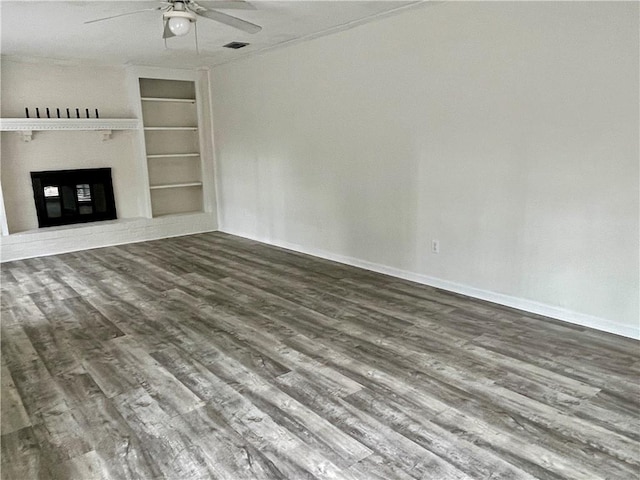 unfurnished living room with ceiling fan, built in shelves, and wood-type flooring