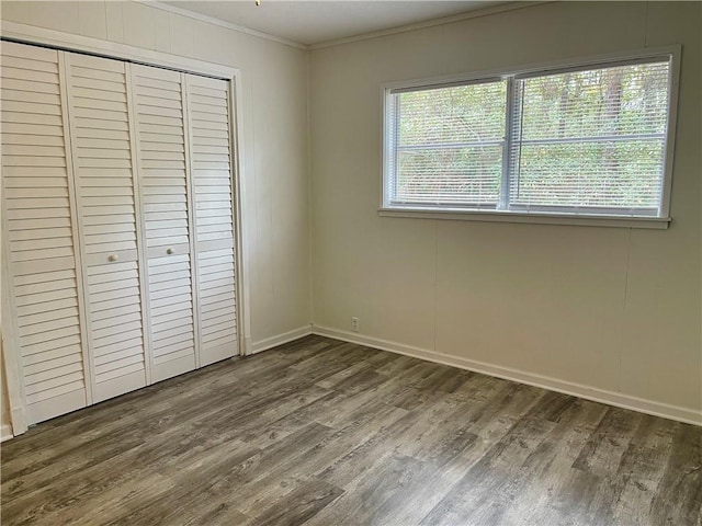 unfurnished bedroom with crown molding, dark hardwood / wood-style floors, and a closet