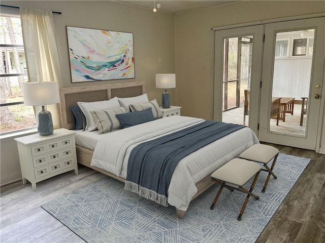 bedroom featuring access to exterior, light hardwood / wood-style floors, multiple windows, and french doors