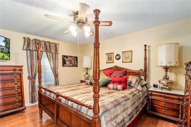 bedroom with a textured ceiling, a ceiling fan, and wood finished floors