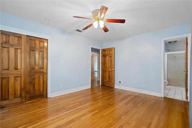 1113 4th Ave, Saraland, AL 36571 - unfurnished bedroom with light wood finished floors, a textured ceiling, connected bathroom, ceiling fan, and a closet